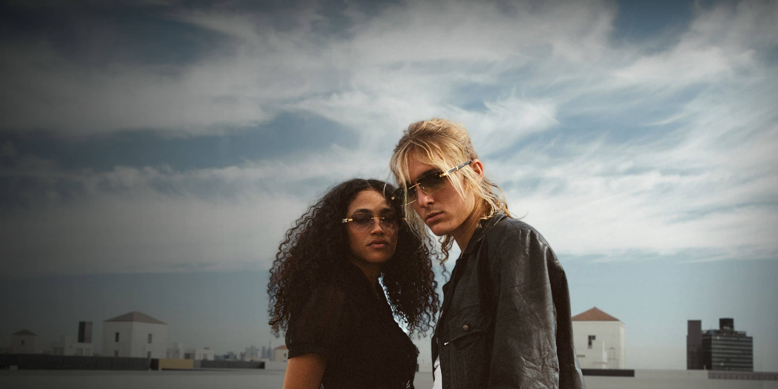 Woman and man wearing sunglasses on rooftop 